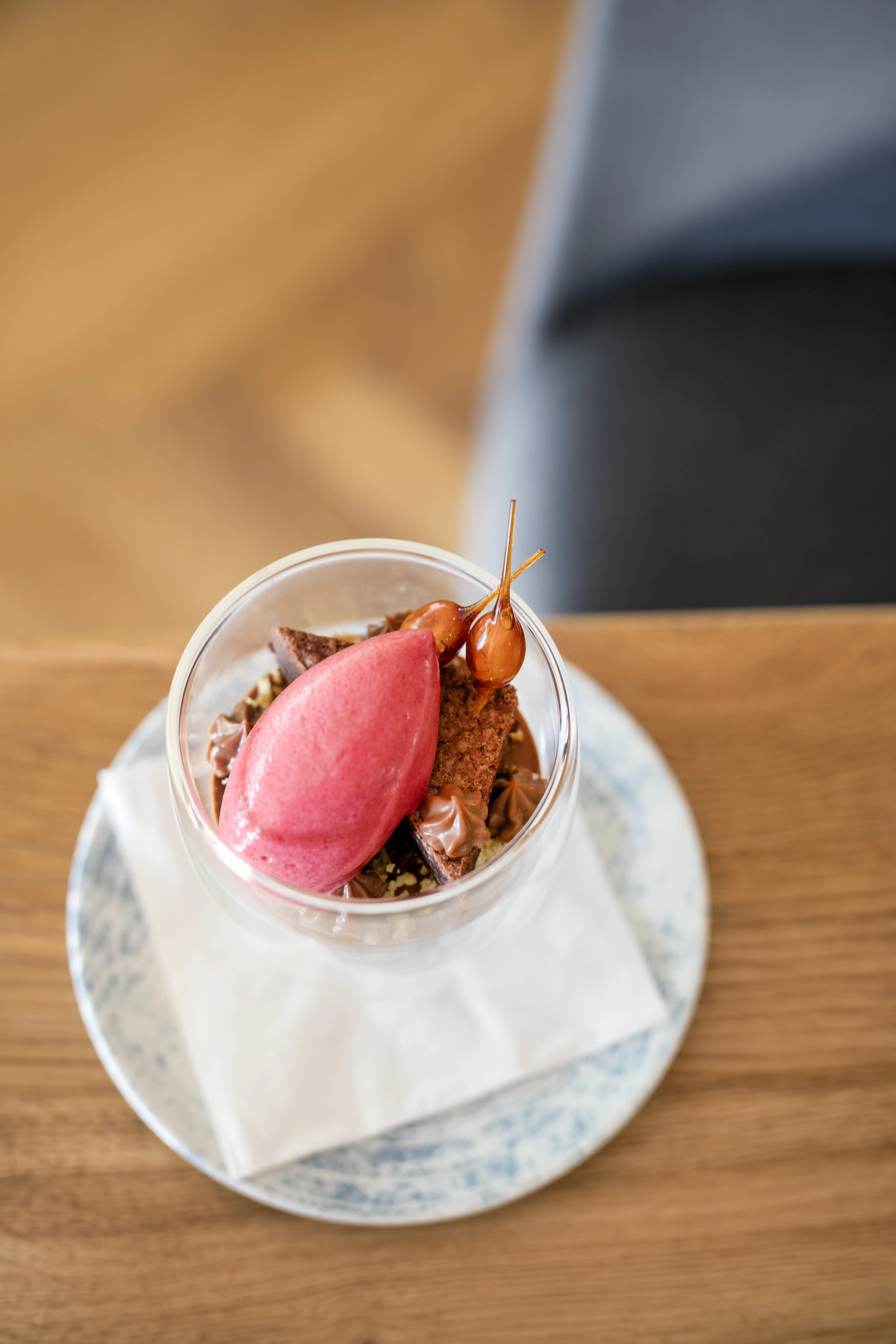 Ein Dessertglas mit pinkem Sorbet, Schokoladenstücken und Deko.
