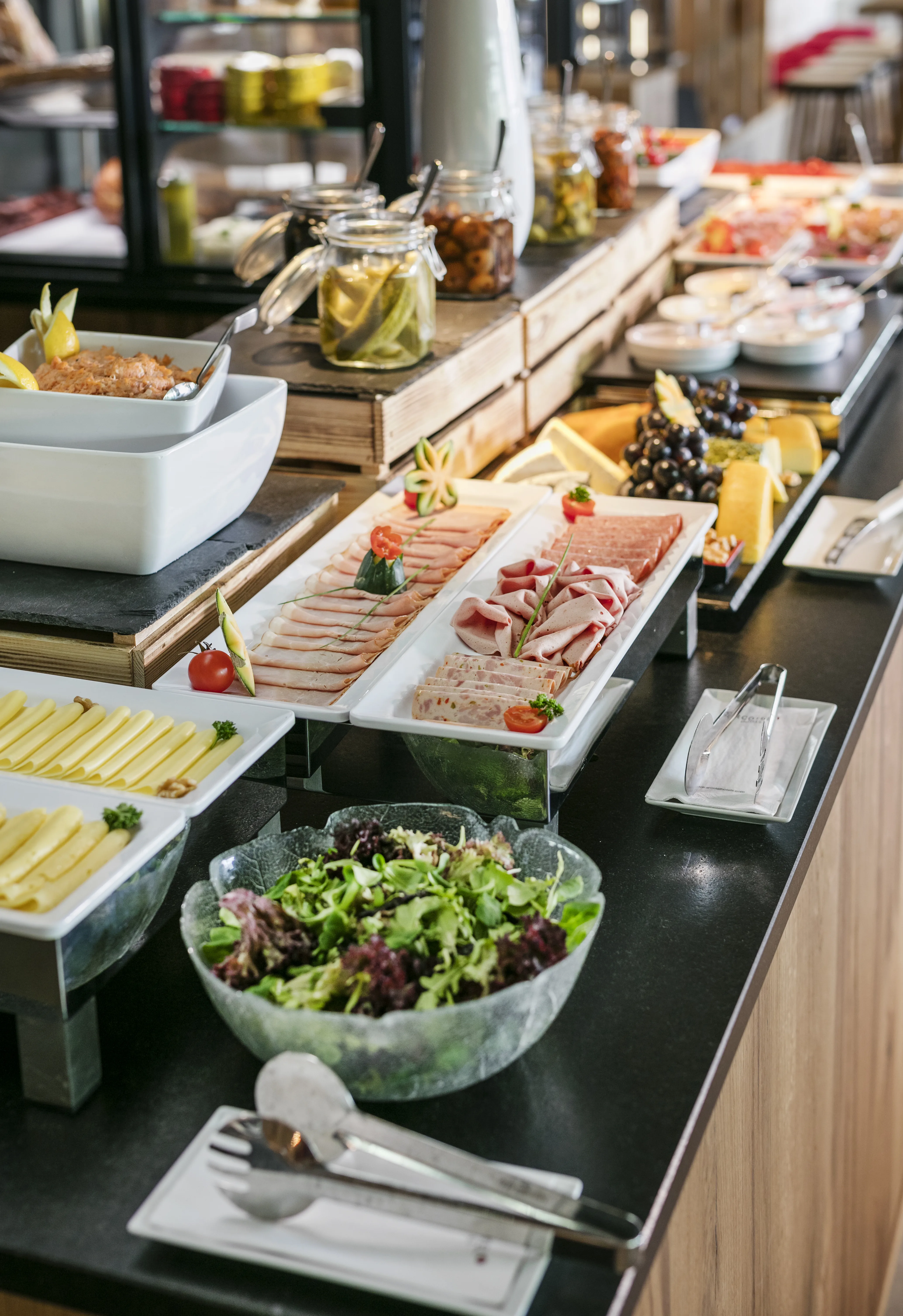 Ein Buffet mit verschiedenen Fleisch- und Käsesorten sowie frischem Salat.