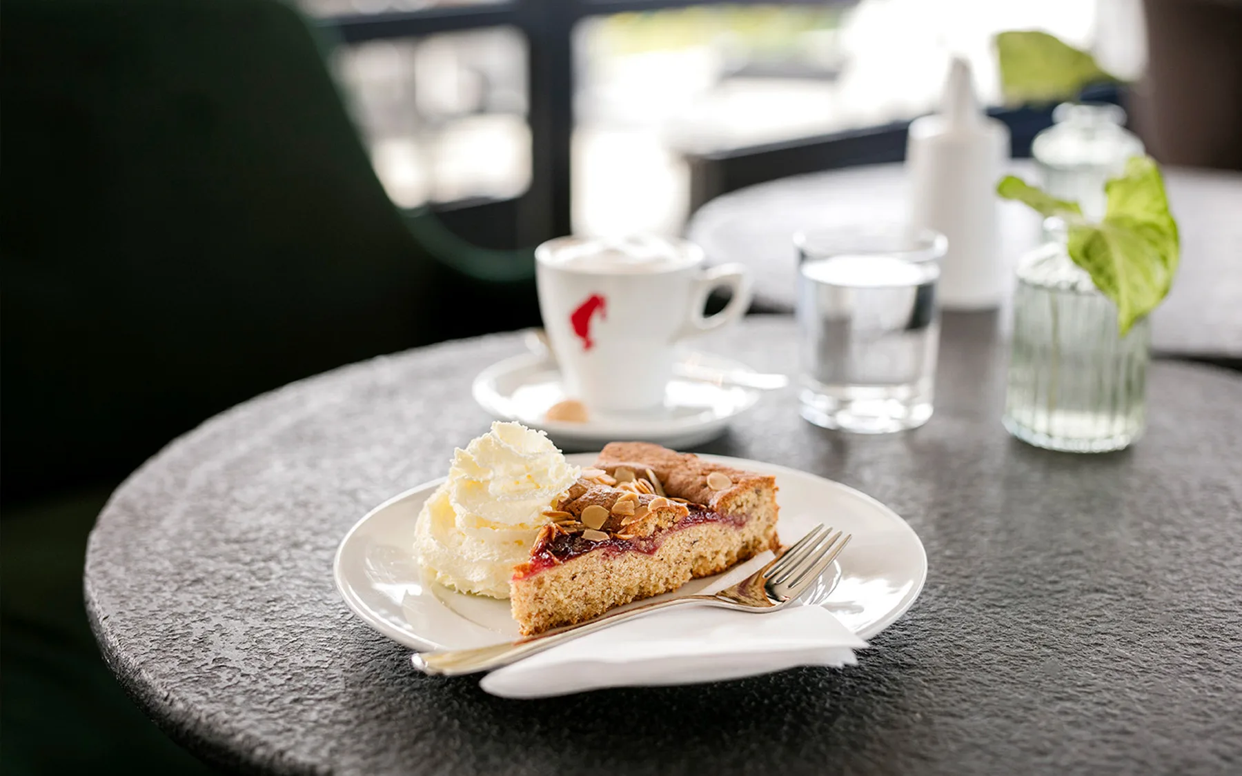 Ein Stück Kuchen mit Sahne und eine Tasse Kaffee auf einem Tisch.