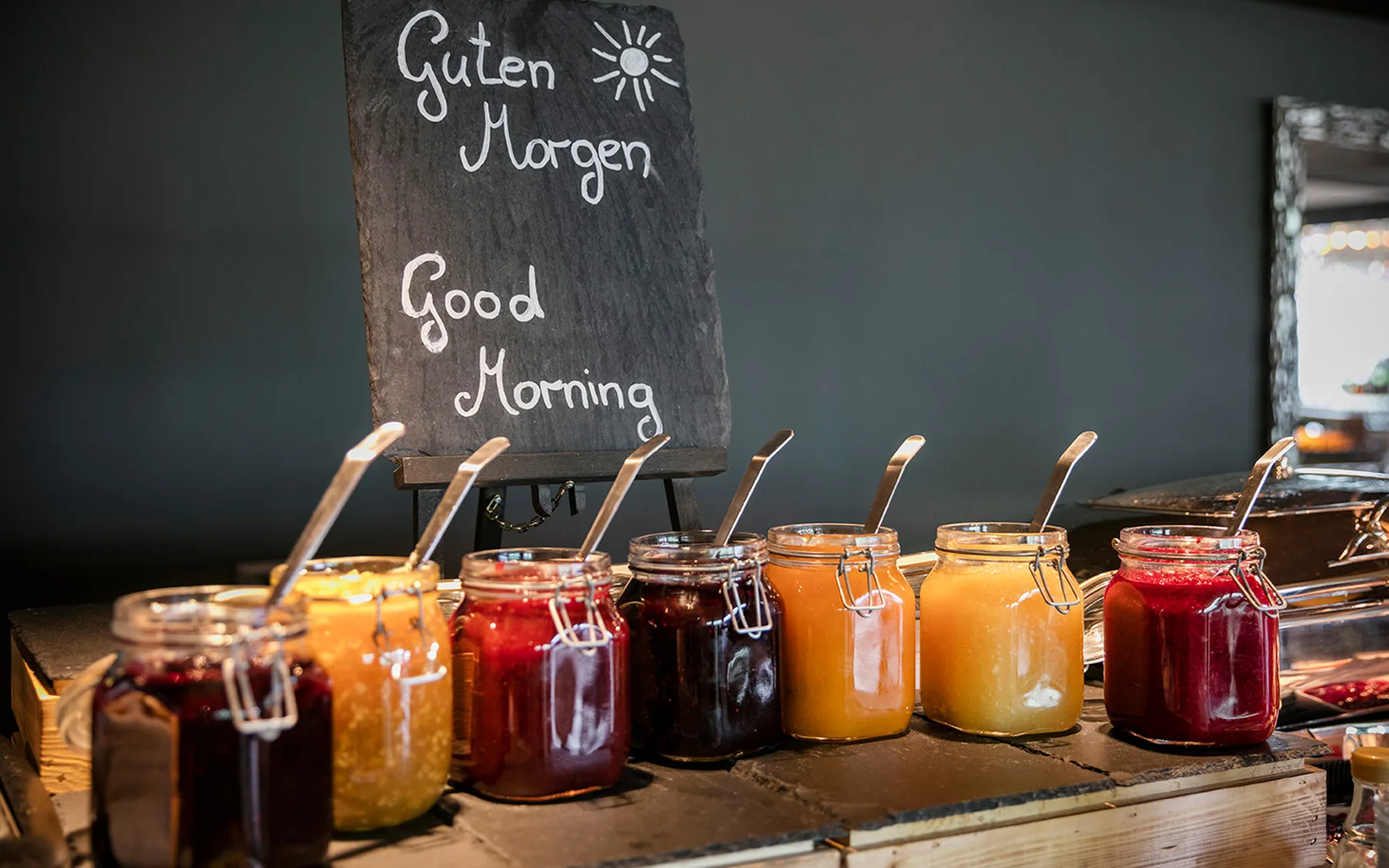Ein Tisch mit verschiedenen Marmeladen und einem Begrüßungsschild.